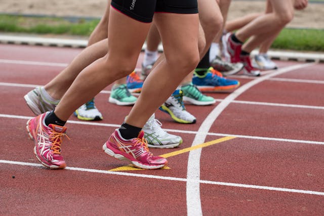 Les jambes de plusieurs jeunes au départ d'une course sur un terrain d'athlétisme